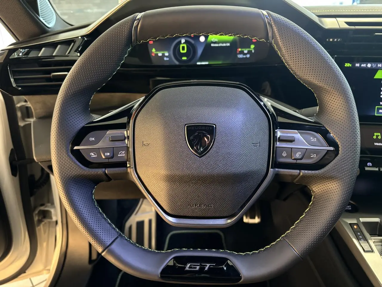Gros plan sur le volant GT en cuir perforé avec surpiqûres vert Adamite de la Peugeot 308 hybride 2026.