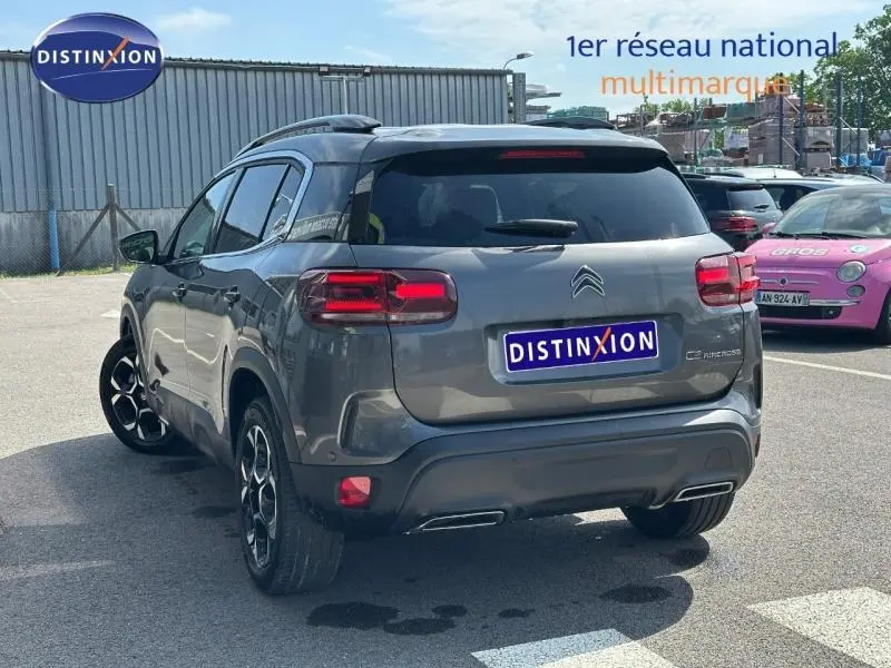 Vue 3/4 arrière droite d'un Citroën C5 Aircross 2025 gris Platinium avec feux arrière LED et jantes noires distinctives.