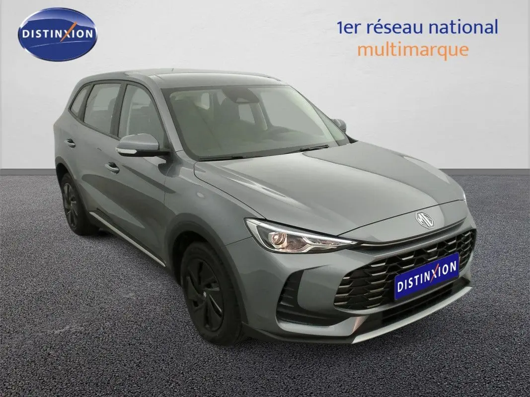 Vue 3/4 avant d’un MG ZS 1.5L hybride gris Hampstead avec calandre noire et jantes foncées.