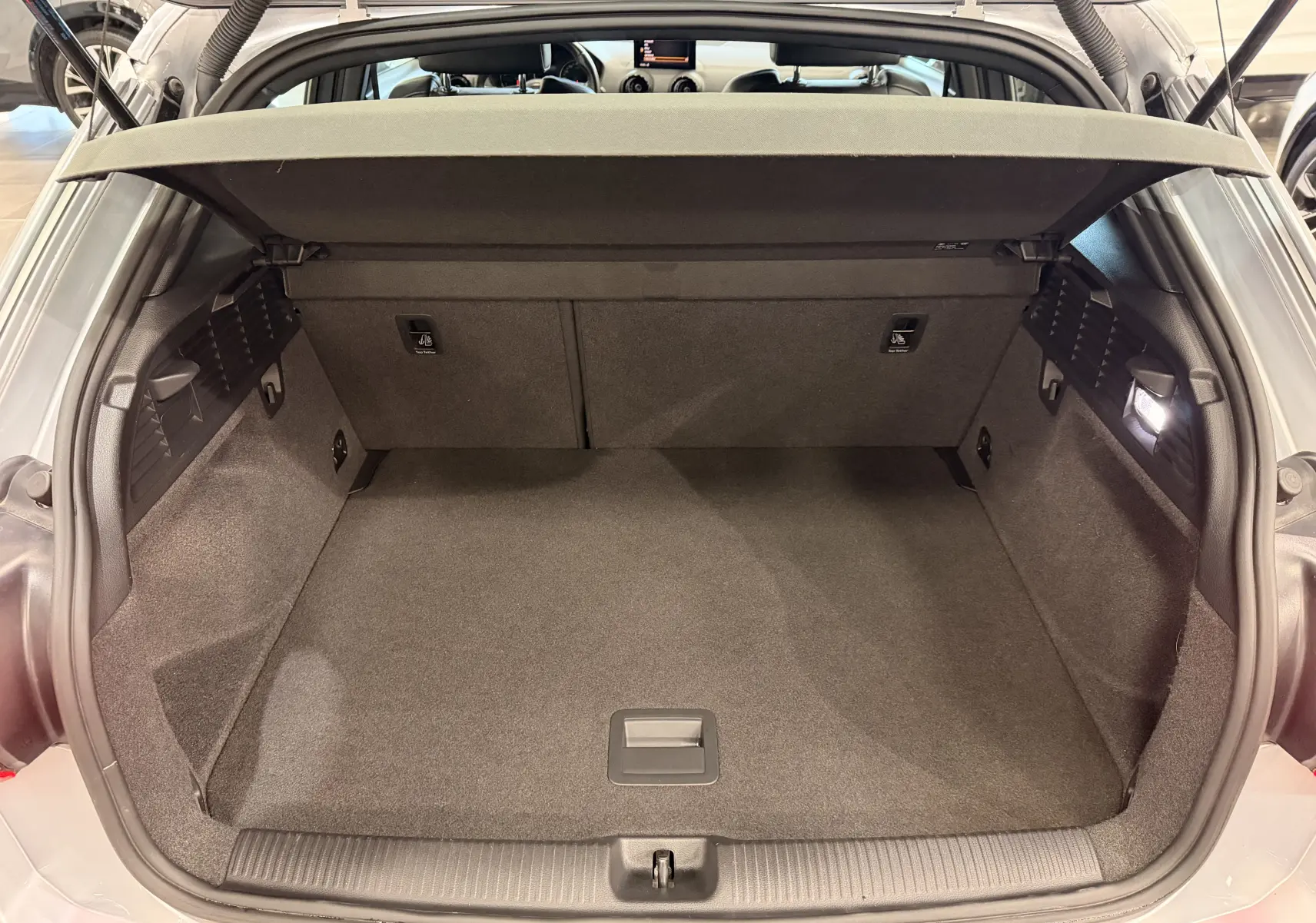 Coffre ouvert vu de l'arrière d'un Audi Q2 gris 2017, montrant un espace de chargement propre et bien éclairé.
