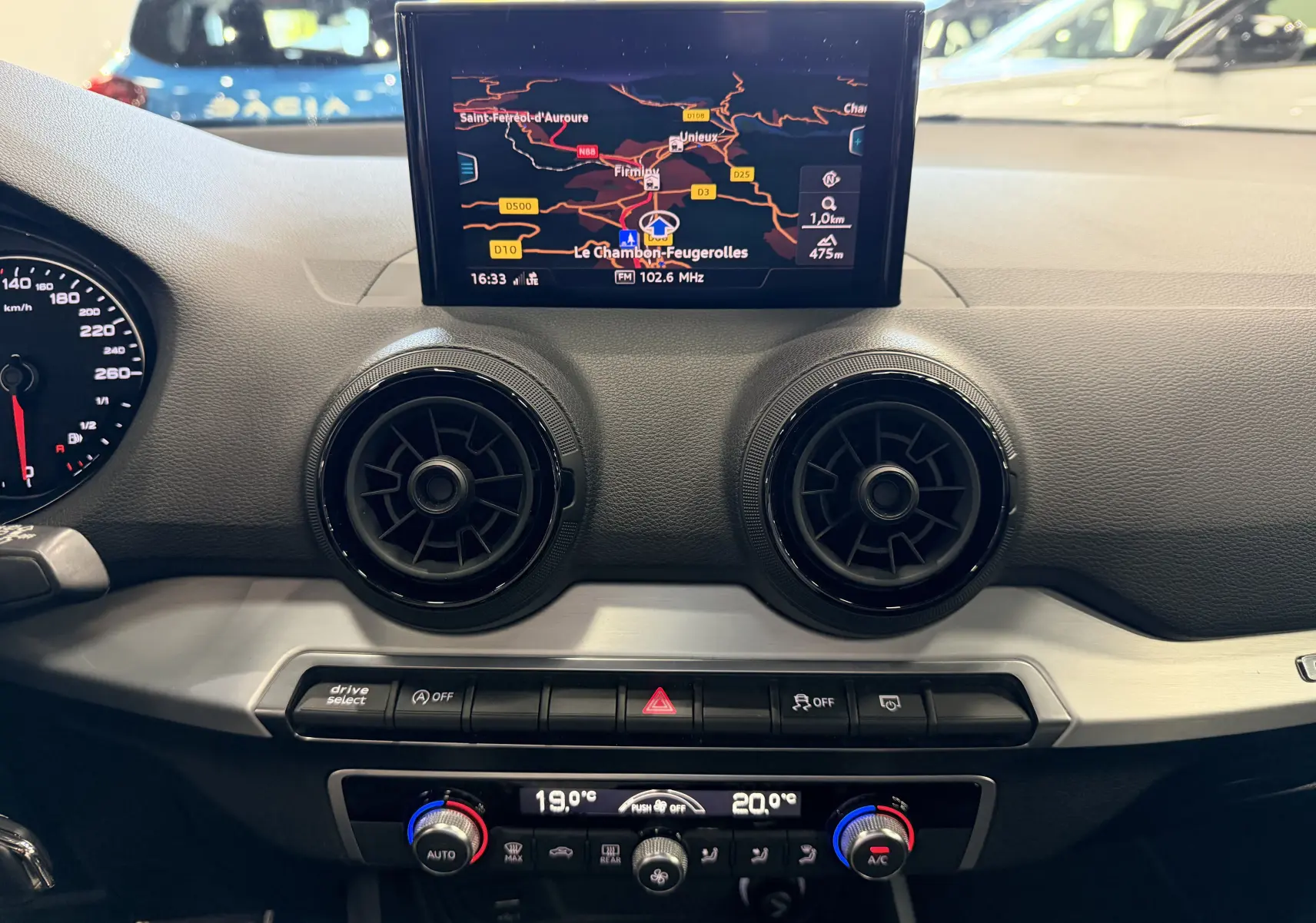 Vue intérieure du tableau de bord de l'Audi Q2 2017 avec écran GPS, aérateurs ronds noirs et commandes de climatisation.