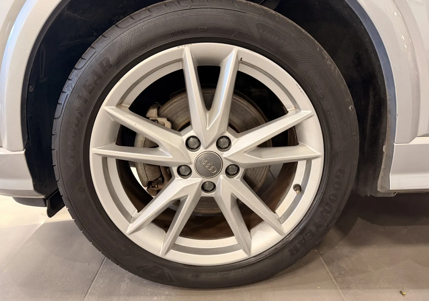 Gros plan sur la roue avant droite grise d’un Audi Q2 2017 avec jante alliage 5 branches doubles et pneu Goodyear.