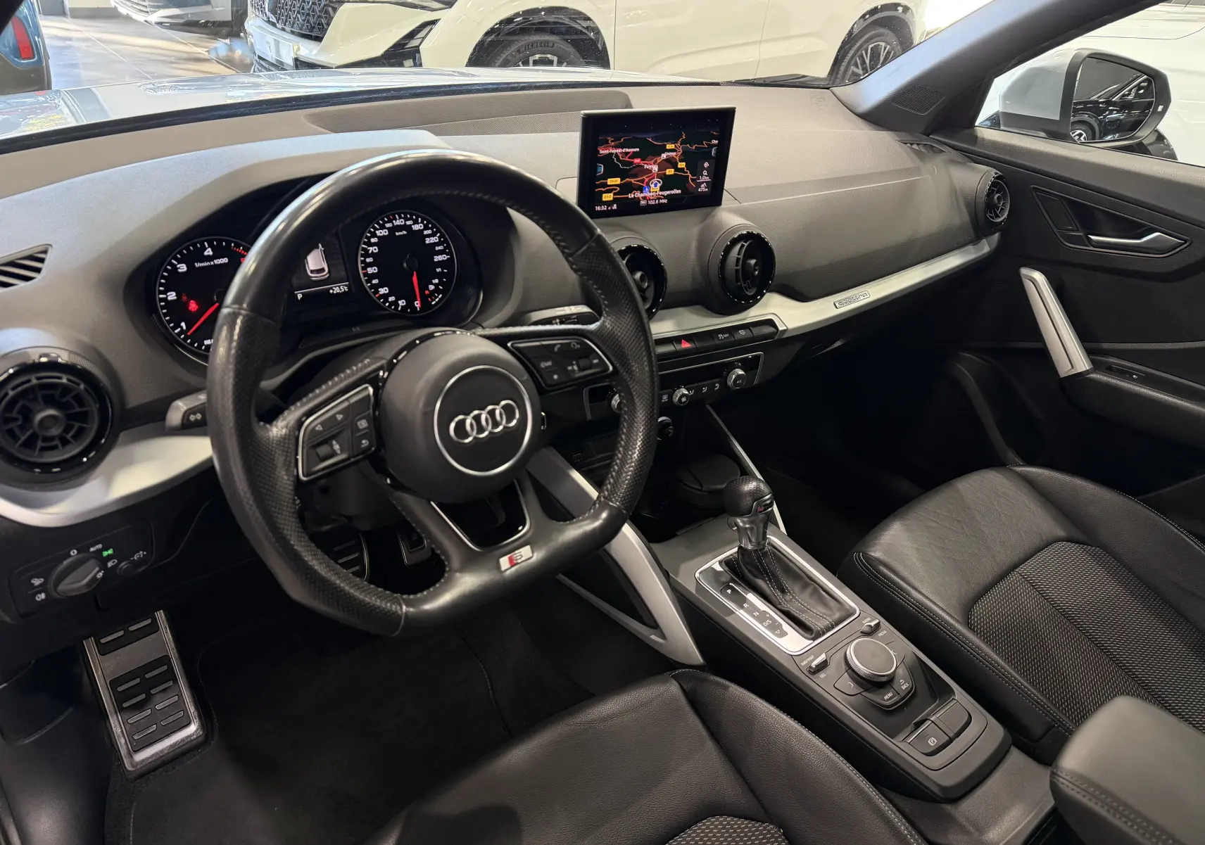 Vue intérieure côté conducteur de l'Audi Q2 2.0 TDI 190 S-Line 2017, avec tableau de bord noir et écran central GPS.