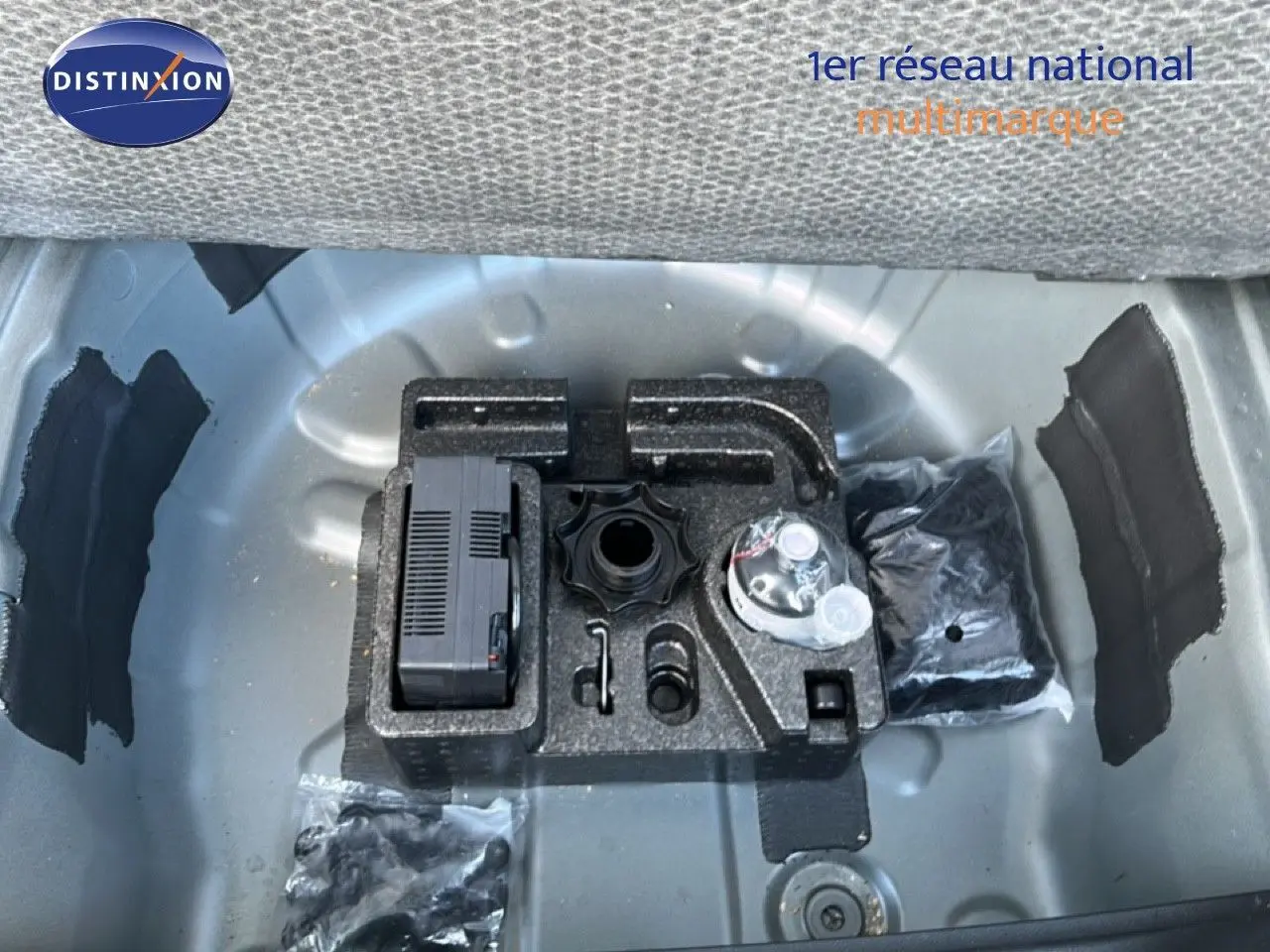 Vue plongeante sur le coffre ouvert d'un SEAT Arona gris falaise métal avec toit blanc, montrant le rangement d'outils intégré.