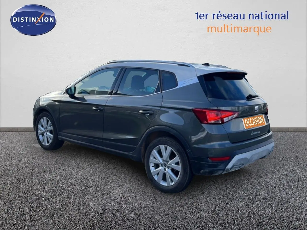 Vue 3/4 arrière gauche d'un SEAT Arona gris falaise métal avec toit blanc, version 2025 essence à boîte automatique.