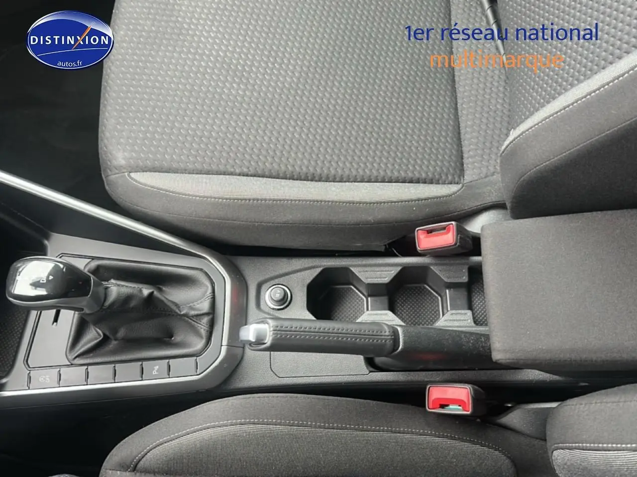 Vue plongeante sur la console centrale noire avec levier de vitesses automatique et accoudoir entre les sièges tissu noir.