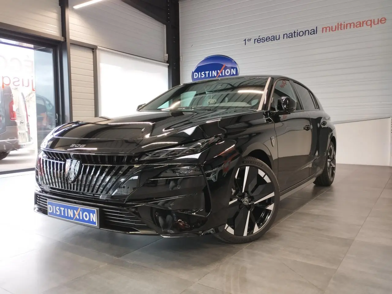 Peugeot 308 hybride noir métallisé vue 3/4 avant en intérieur avec calandre et jantes distinctives.