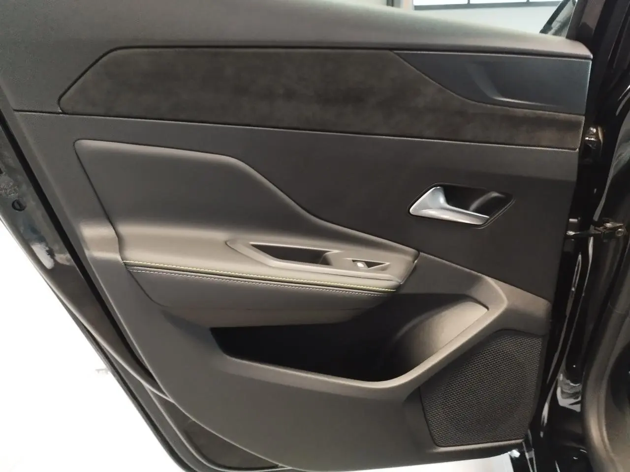 Intérieur de la porte arrière droite d’une Peugeot 308 noire, avec surpiqûres vert Adamite et insert Alcantara.