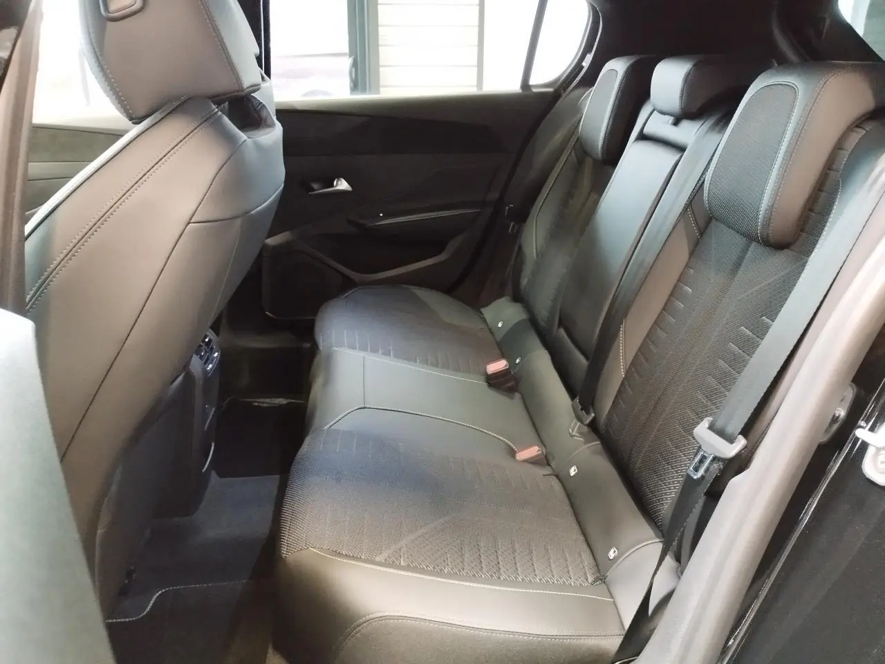 Vue intérieure côté droit des sièges arrière en tissu noir et similicuir du Peugeot 308 1.2i Hybrid 2026 noir métallisé.