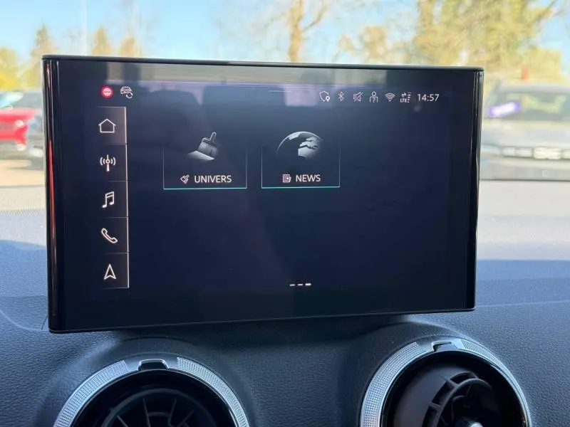 Écran tactile central de l'Audi Q2 35 TDI S line 2025 affichant les menus Univers et News, avec aérateurs ronds en dessous