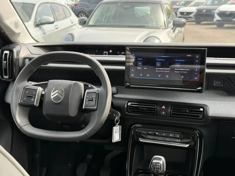 Vue intérieure centrée sur le volant et l’écran tactile de la Citroën C3 1.2 Turbo 100ch gris Mercury, avec levier de vitesse manuel.