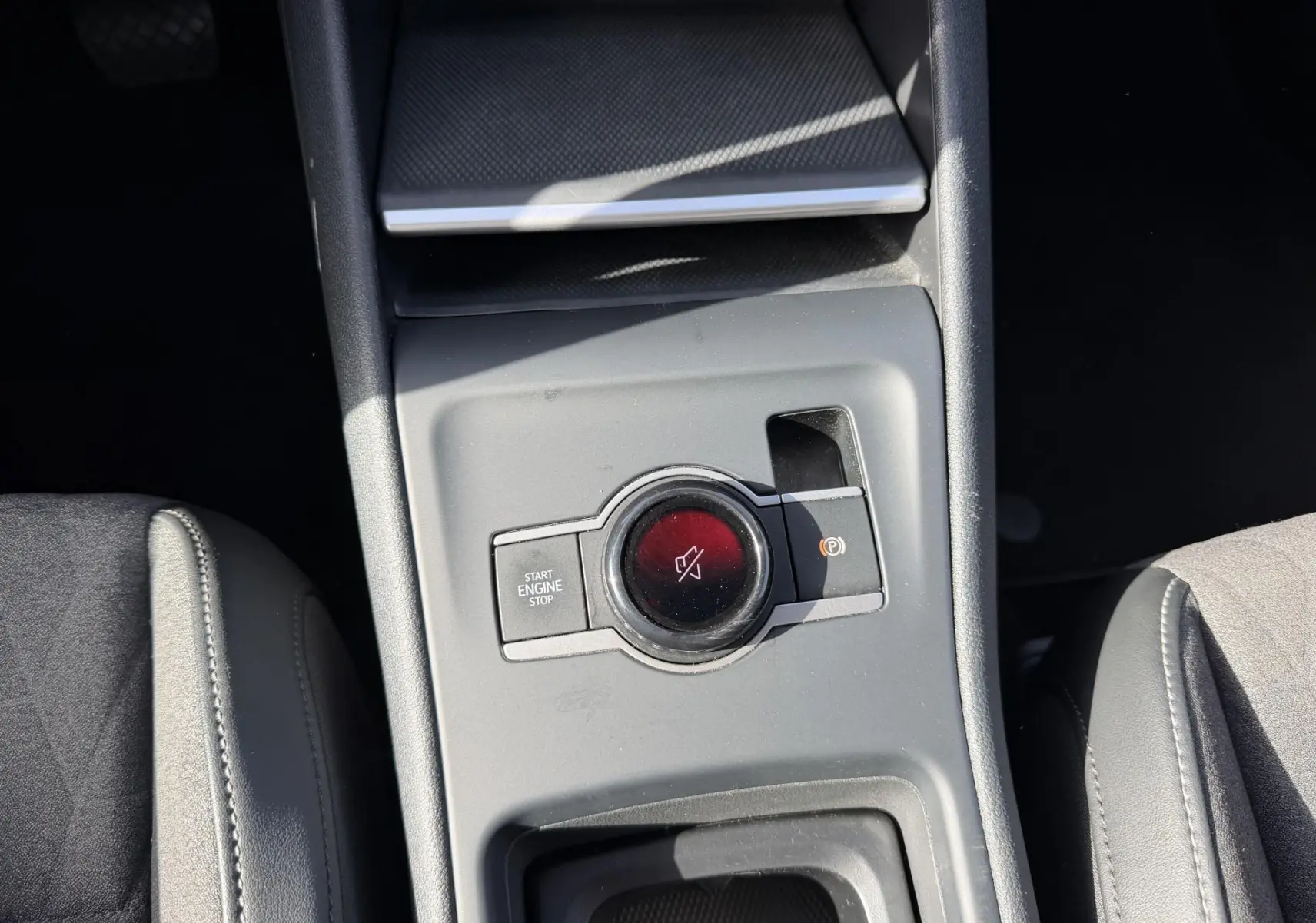 Gros plan sur la console centrale grise du Volkswagen Tiguan 2025, montrant le bouton Start/Stop et frein de stationnement électronique.