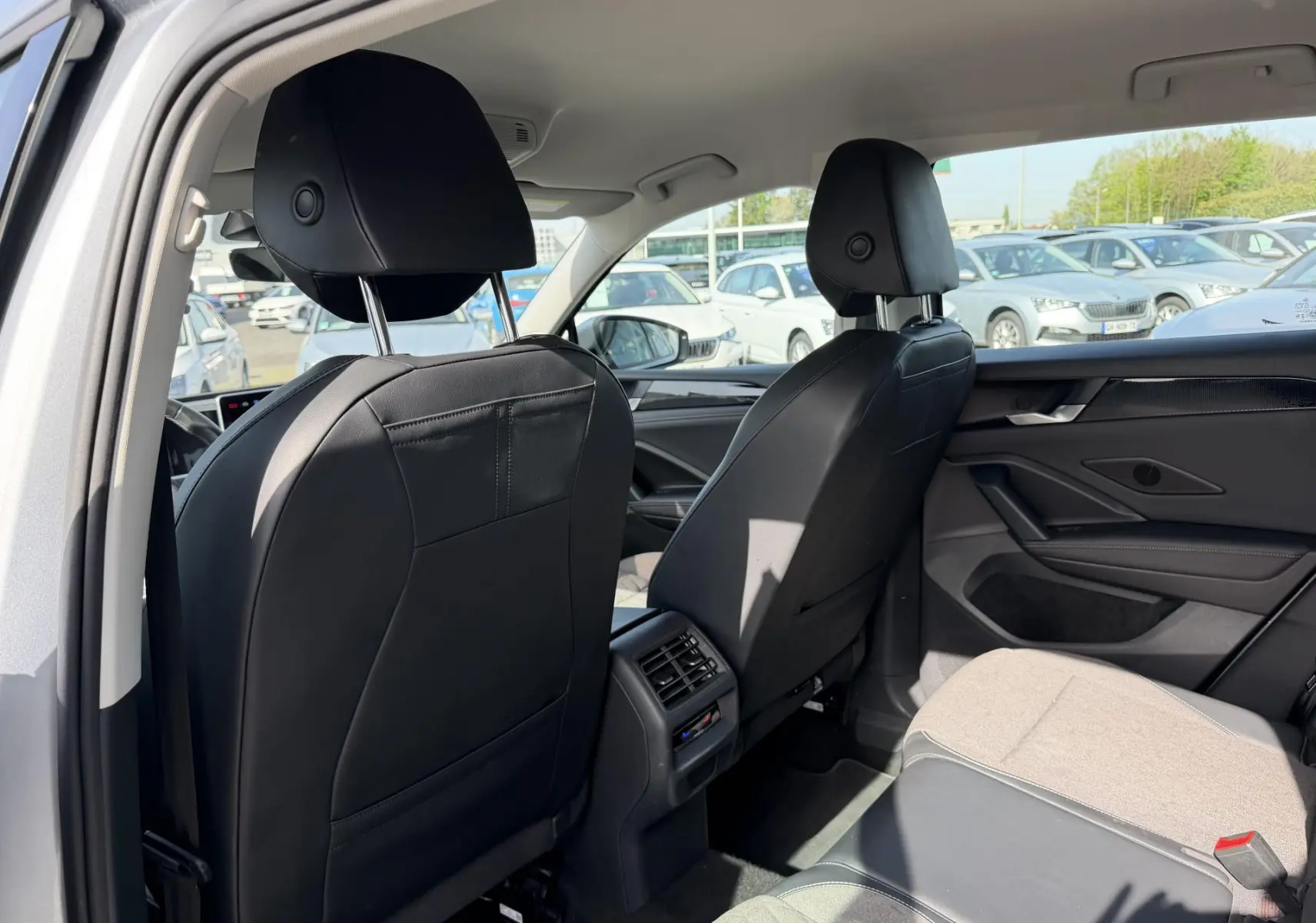 Vue arrière intérieure du Volkswagen Tiguan gris 2025, montrant les sièges avant en cuir noir et la banquette arrière partiellement en tissu clair.