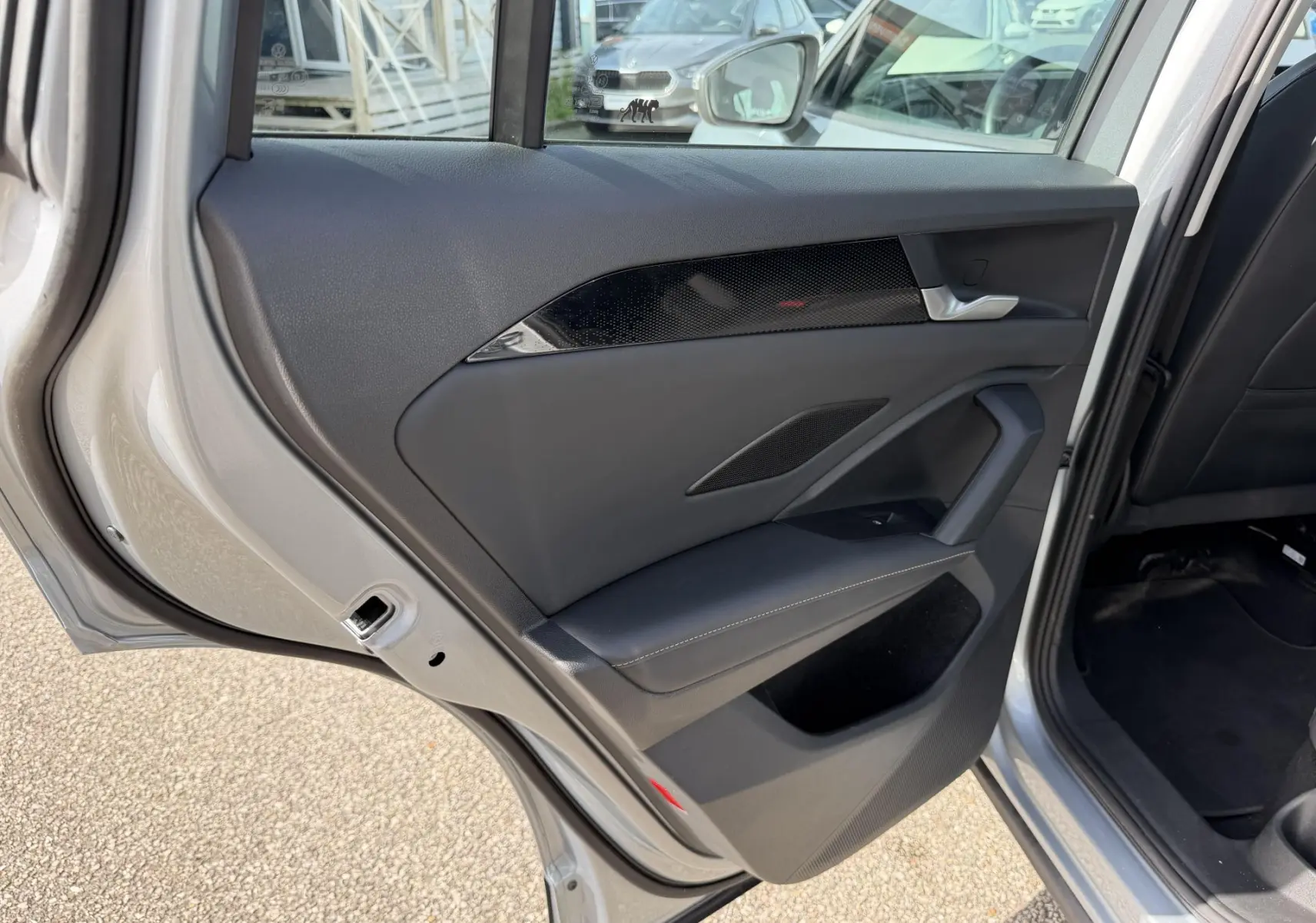 Vue rapprochée de la porte arrière gauche grise du Volkswagen Tiguan 2025, avec garniture noire et insert décoratif brillant.