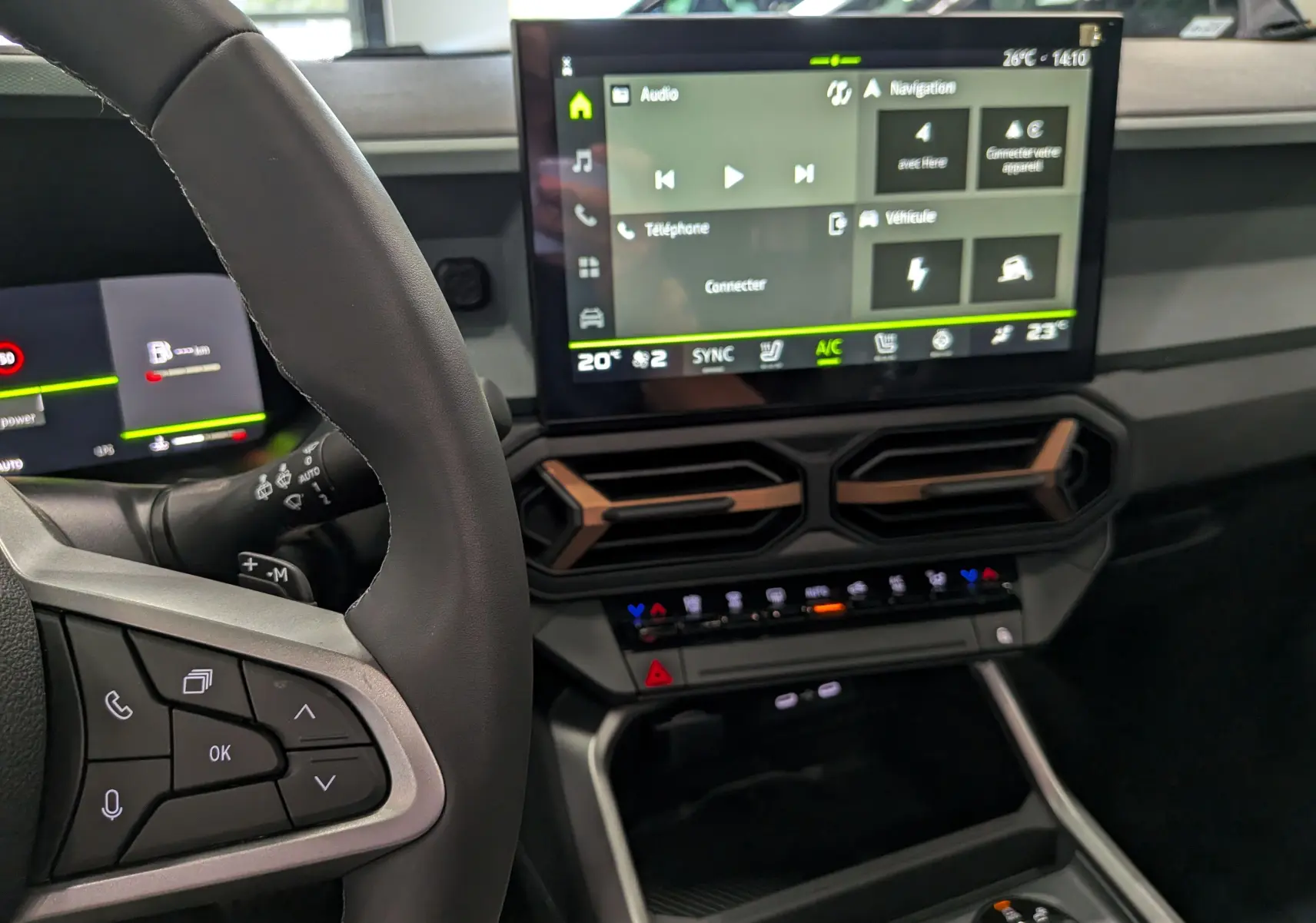 Vue intérieure du tableau de bord du Dacia Bigster Hybrid-G 150 4x4, avec écran tactile central et volant partiel en cuir noir.