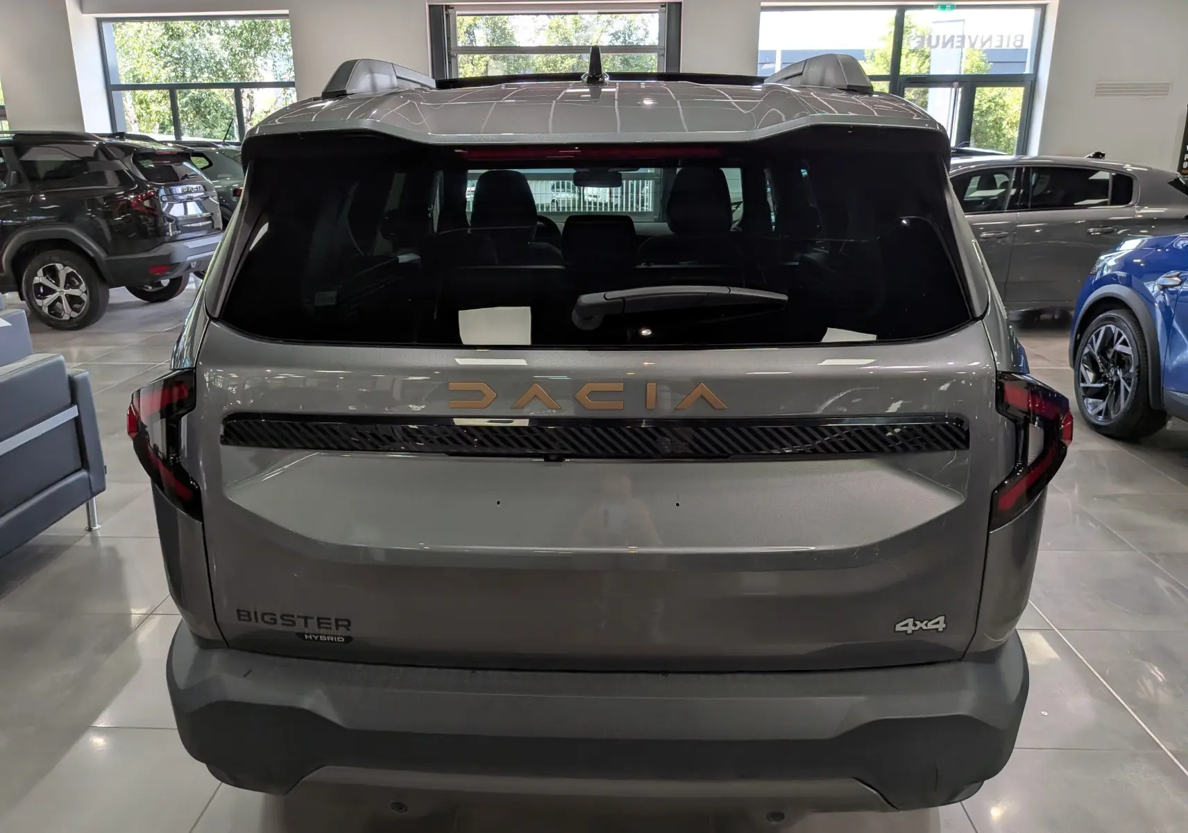 Vue arrière du Dacia Bigster Hybrid-G 150 4x4 gris schiste, avec logo doré et feux arrière LED distinctifs.