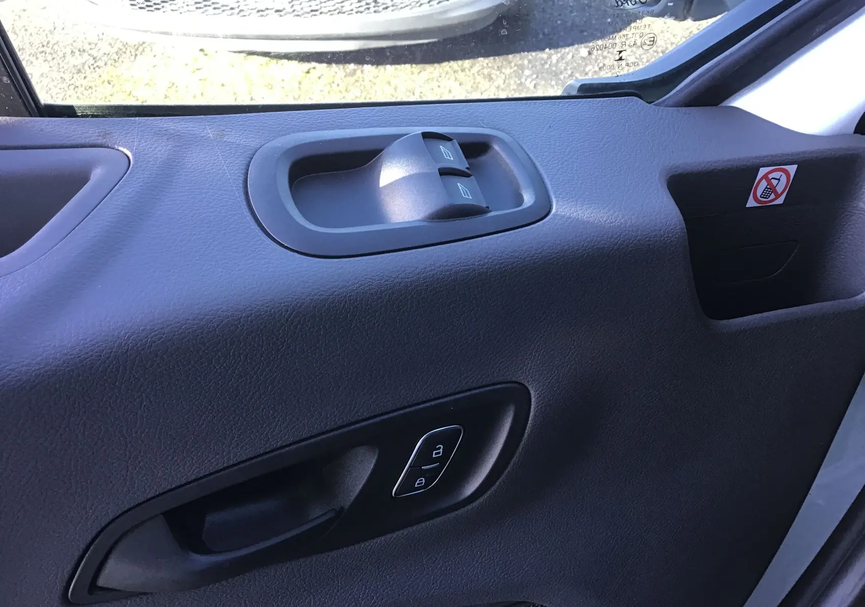 Gros plan sur la porte intérieure côté conducteur du Ford Transit blanc, montrant les commandes de vitres et de verrouillage.