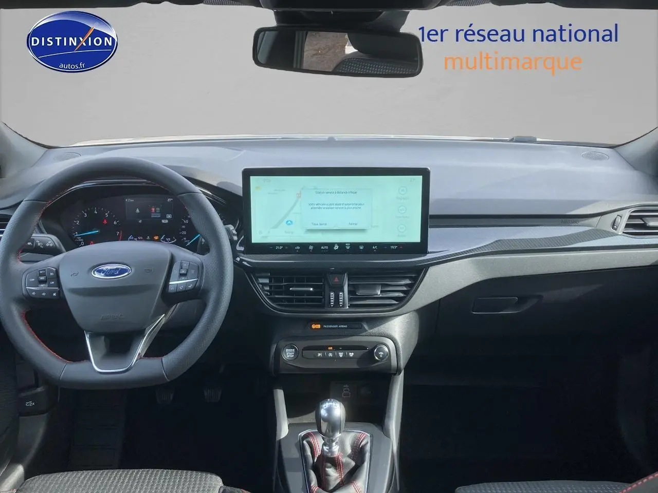 Intérieur Ford Focus 2025 vue tableau de bord avec écran tactile 13,2'', volant cuir noir à coutures rouges et levier manuel.