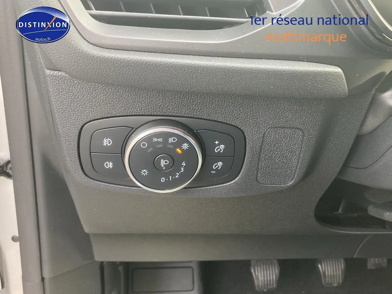 Gros plan sur le tableau de bord côté gauche de la Ford Focus gris, avec commandes d'éclairage et pédales visibles.