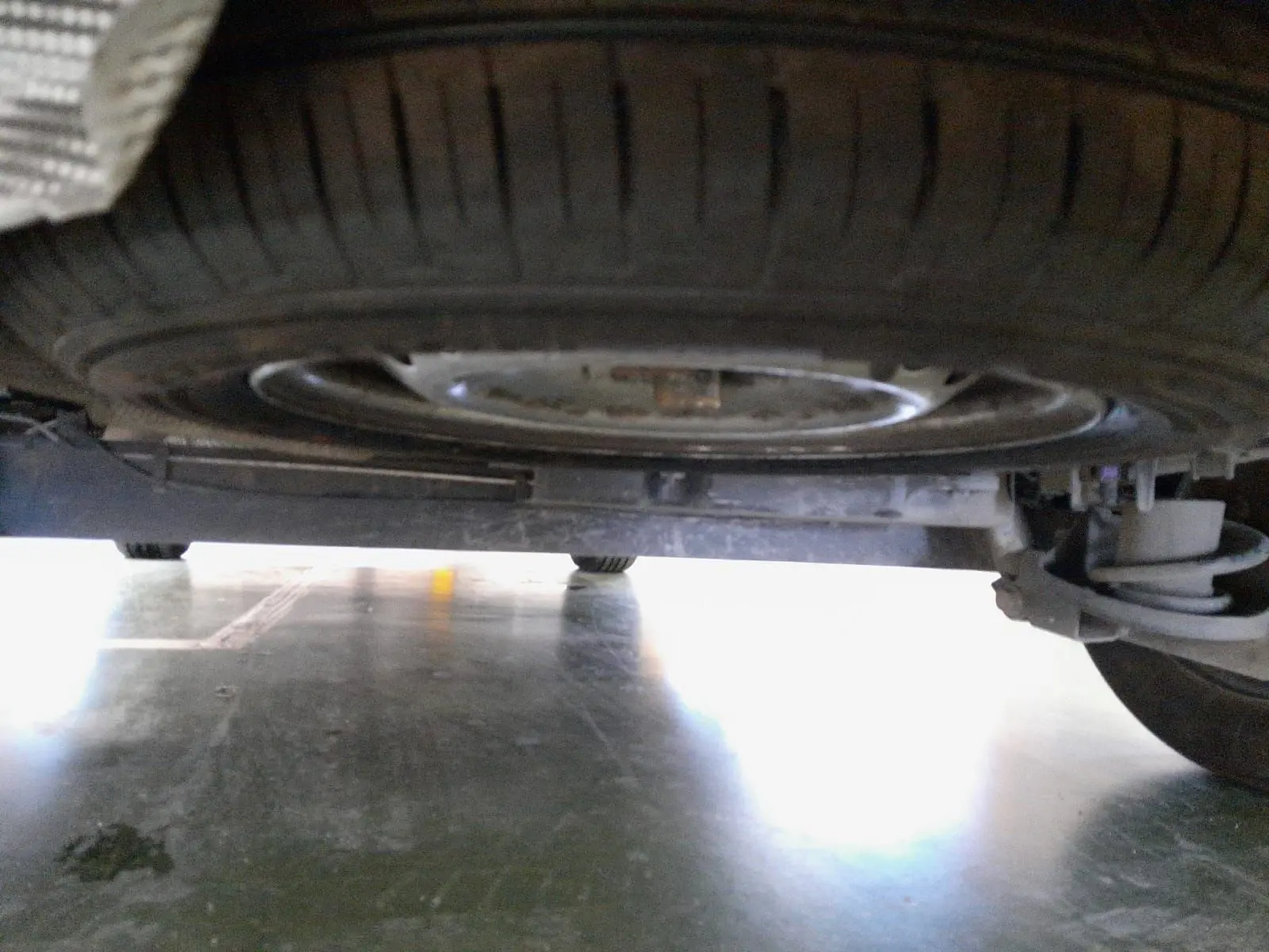 Vue en contre-plongée sous un Renault Express Van blanc 2023, montrant la roue de secours et la suspension arrière.