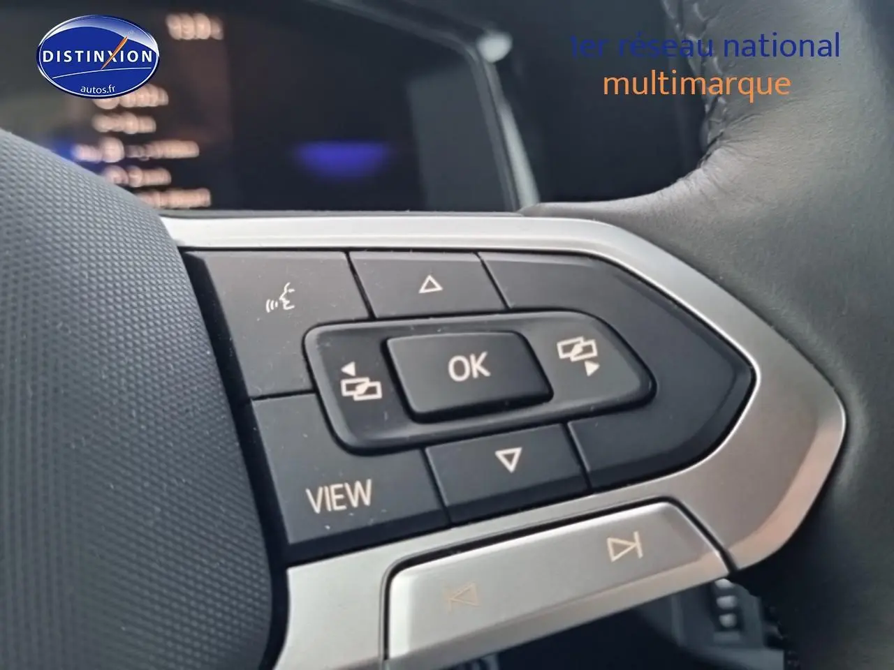 Gros plan sur les commandes multifonctions noires et argent du volant cuir d'une Volkswagen Polo 2025 noir intense nacré.