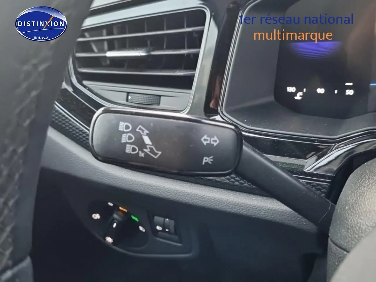 Détail intérieur du volant côté gauche d’une Volkswagen Polo noire avec commandes des phares et tableau de bord digital.