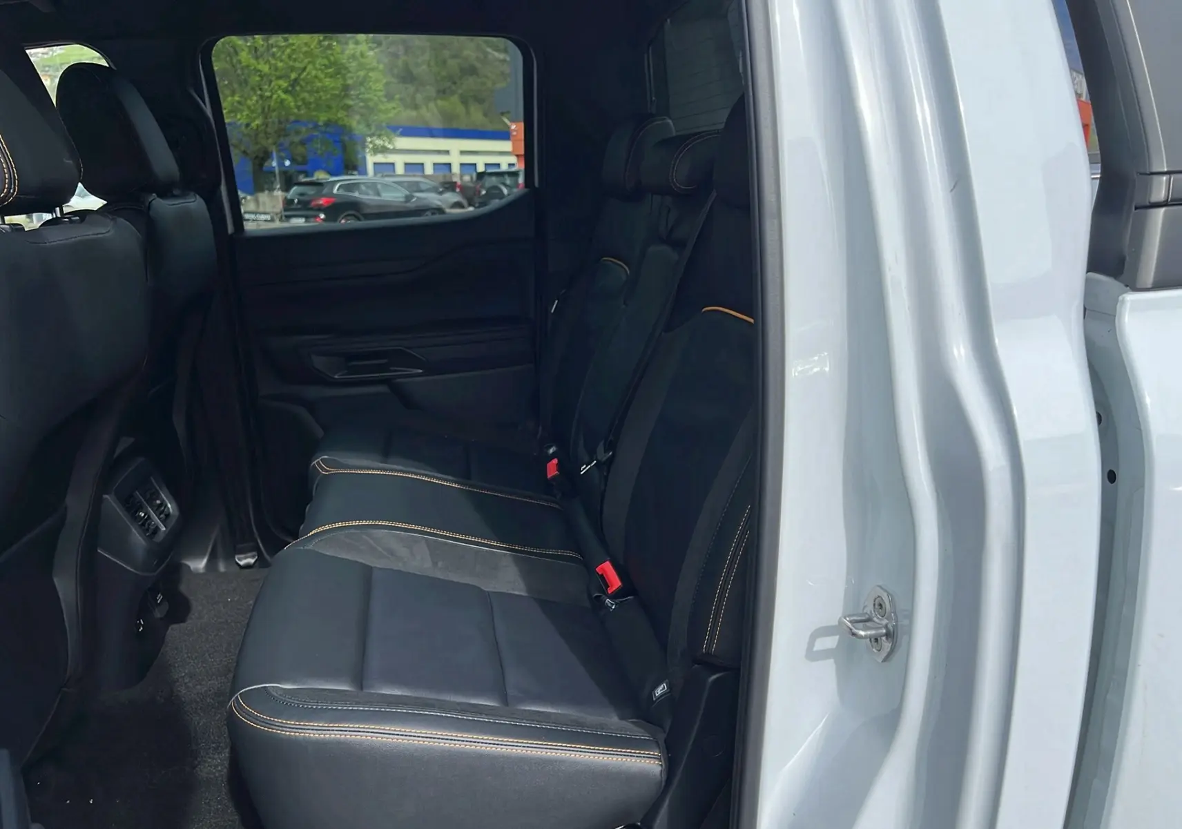 Vue intérieure côté droit des sièges arrière en cuir noir avec surpiqûres orange du Ford Ranger blanc glacier 2025.