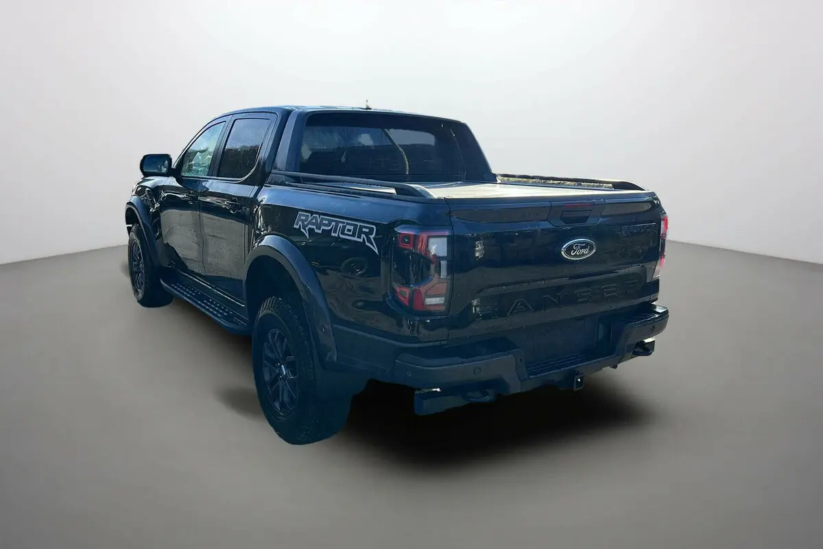 Vue 3/4 arrière gauche du Ford Ranger Raptor noir absolu avec logo Raptor sur la benne et jantes noires.