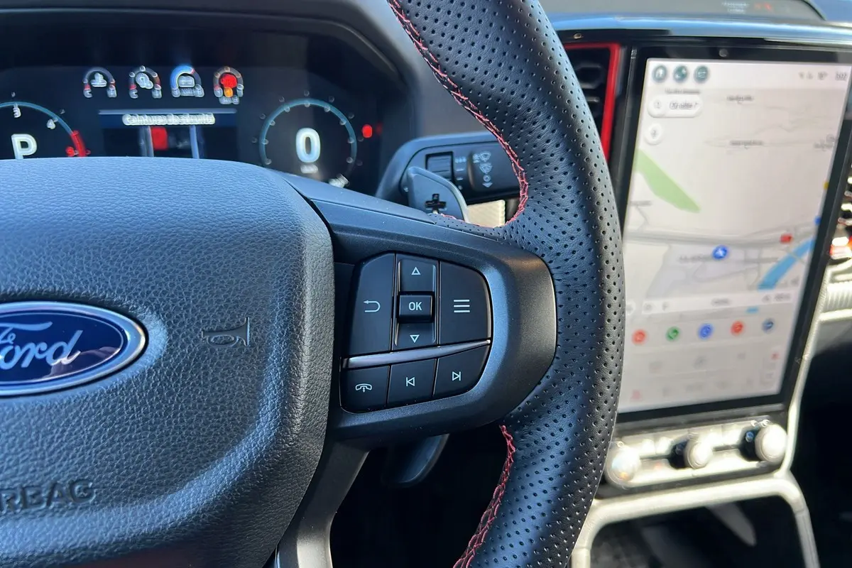 Vue rapprochée du volant en cuir perforé avec surpiqûres rouges et écran tactile vertical du Ford Ranger Raptor 2025.