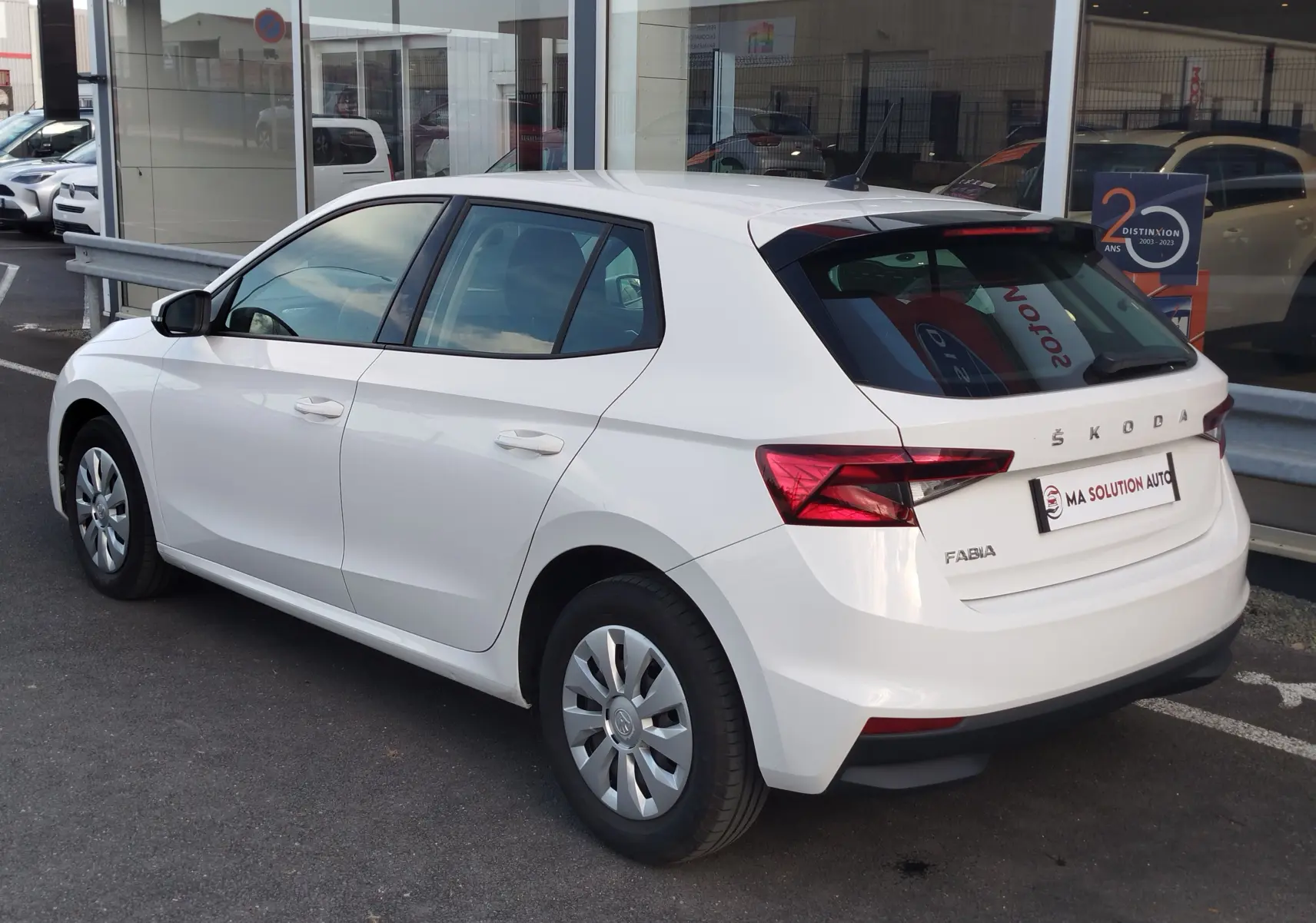 Vue 3/4 arrière droite d'une Skoda Fabia blanche Lune 2022, avec feux arrière LED et jantes acier.