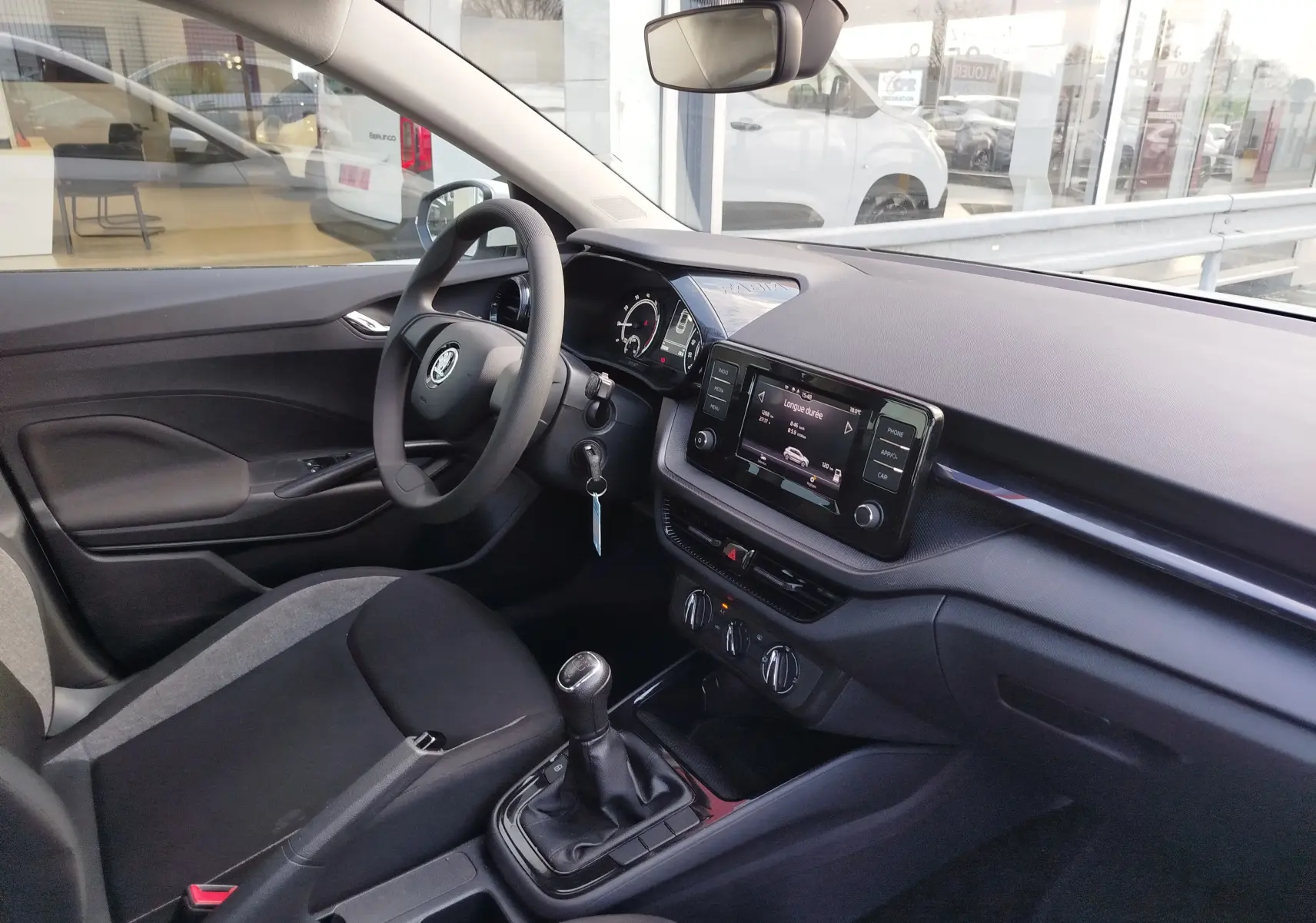 Vue intérieure côté conducteur de la Skoda Fabia 2022, tableau de bord noir avec écran tactile et boîte manuelle.