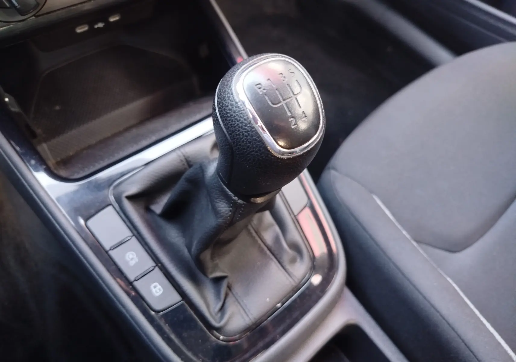 Gros plan sur le levier de vitesses manuel noir dans l’habitacle gris foncé de la Skoda Fabia 2022.