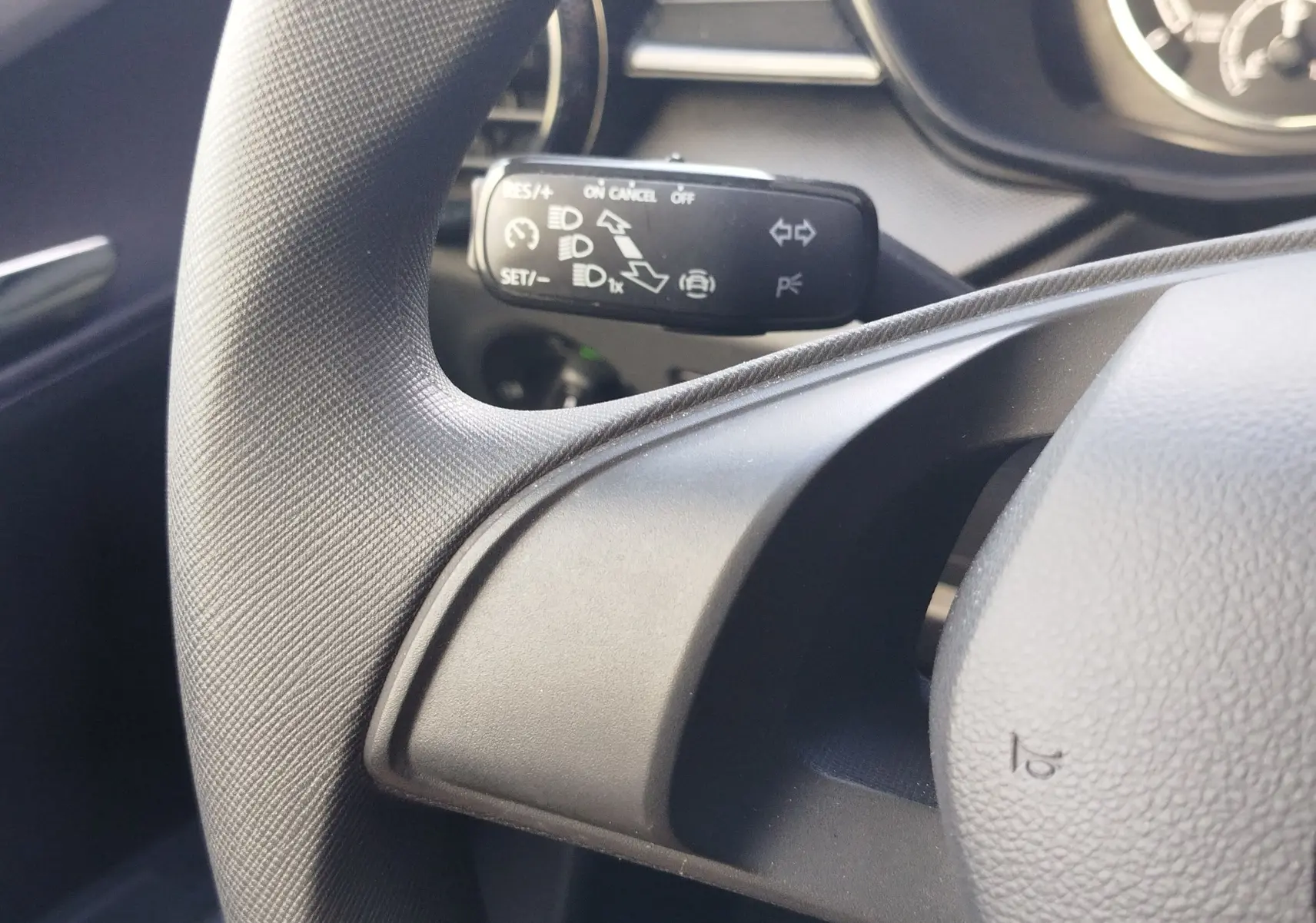 Gros plan sur le commodo gauche du volant d’une Skoda Fabia 2022, intérieur gris avec commandes de régulateur de vitesse.