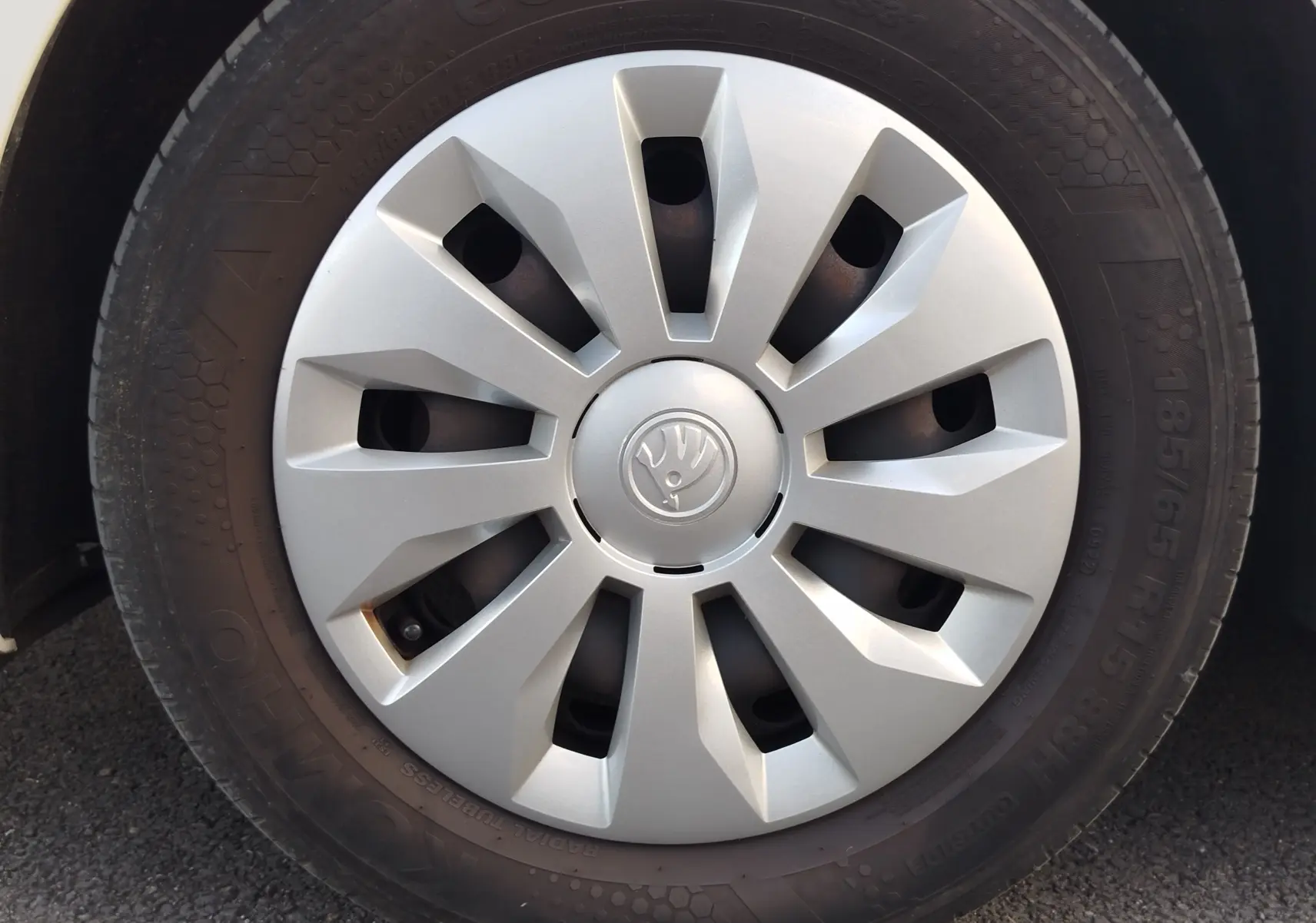 Gros plan sur la roue avant gauche de la Skoda Fabia blanc lune 2022 avec enjoliveur argenté et logo central.