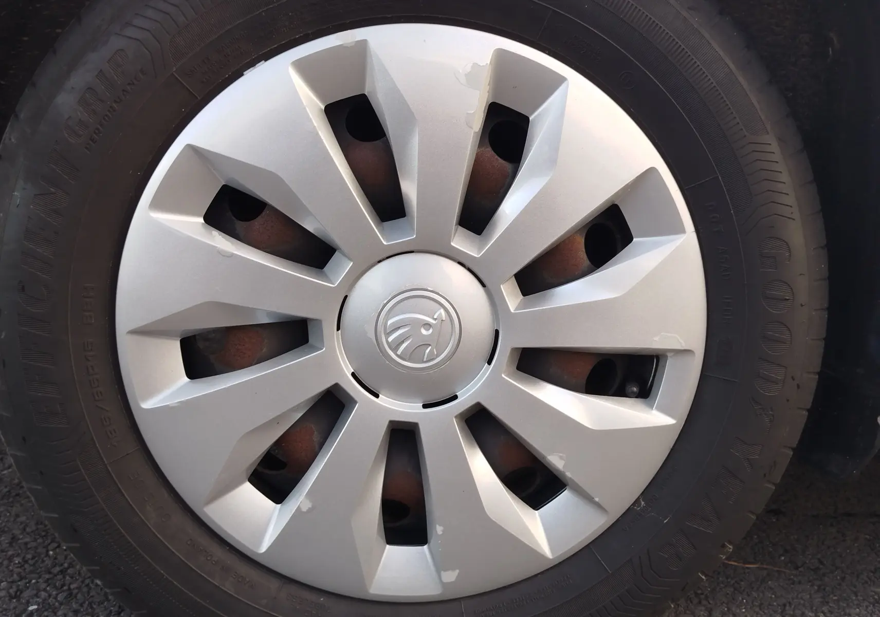 Gros plan sur la roue avant droite d'une Skoda Fabia blanc lune, avec enjoliveur argenté et logo central visible.