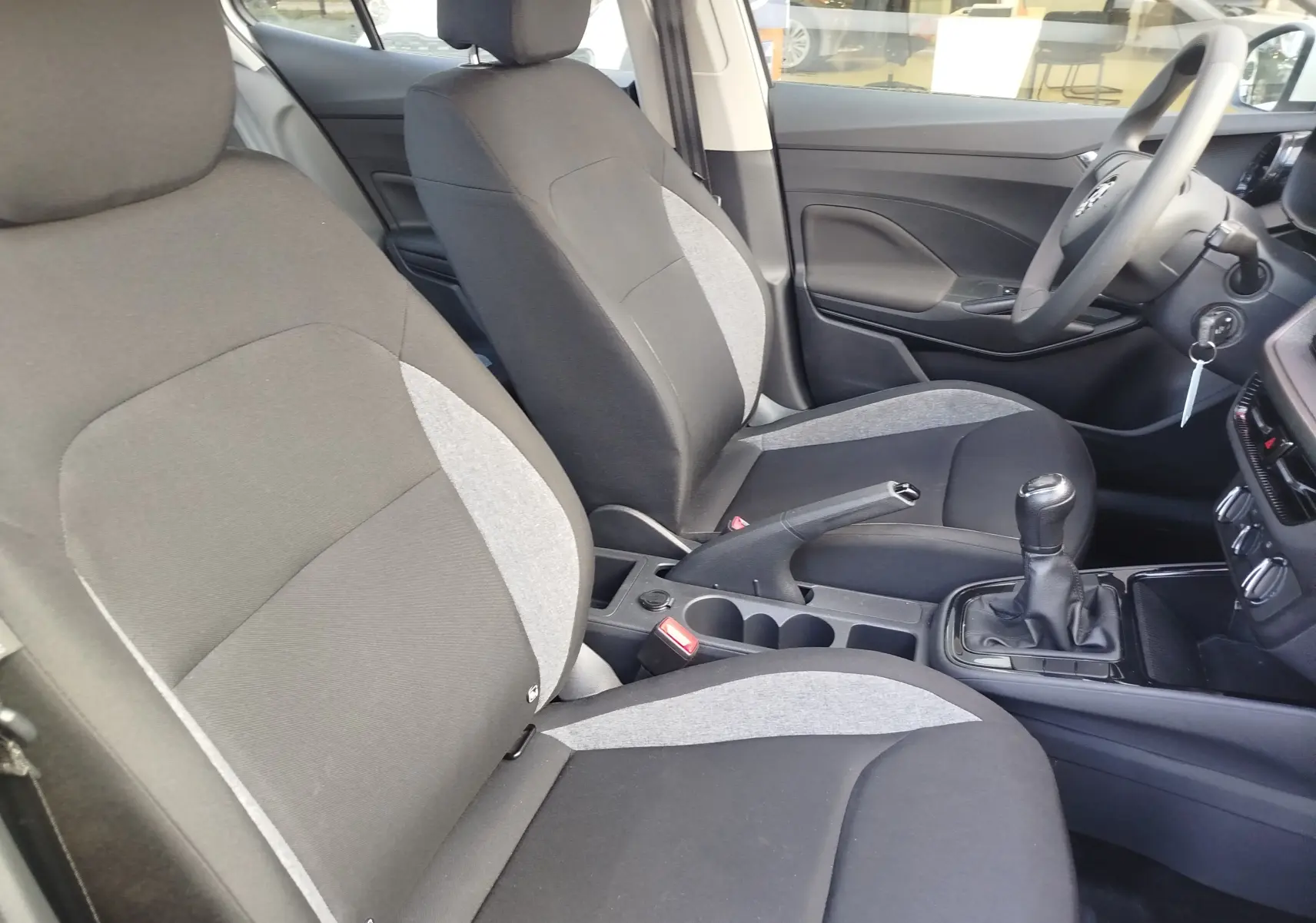 Vue intérieure côté droit de la Skoda Fabia 2022, sièges tissu bicolore gris et noir avec levier de vitesse manuel.