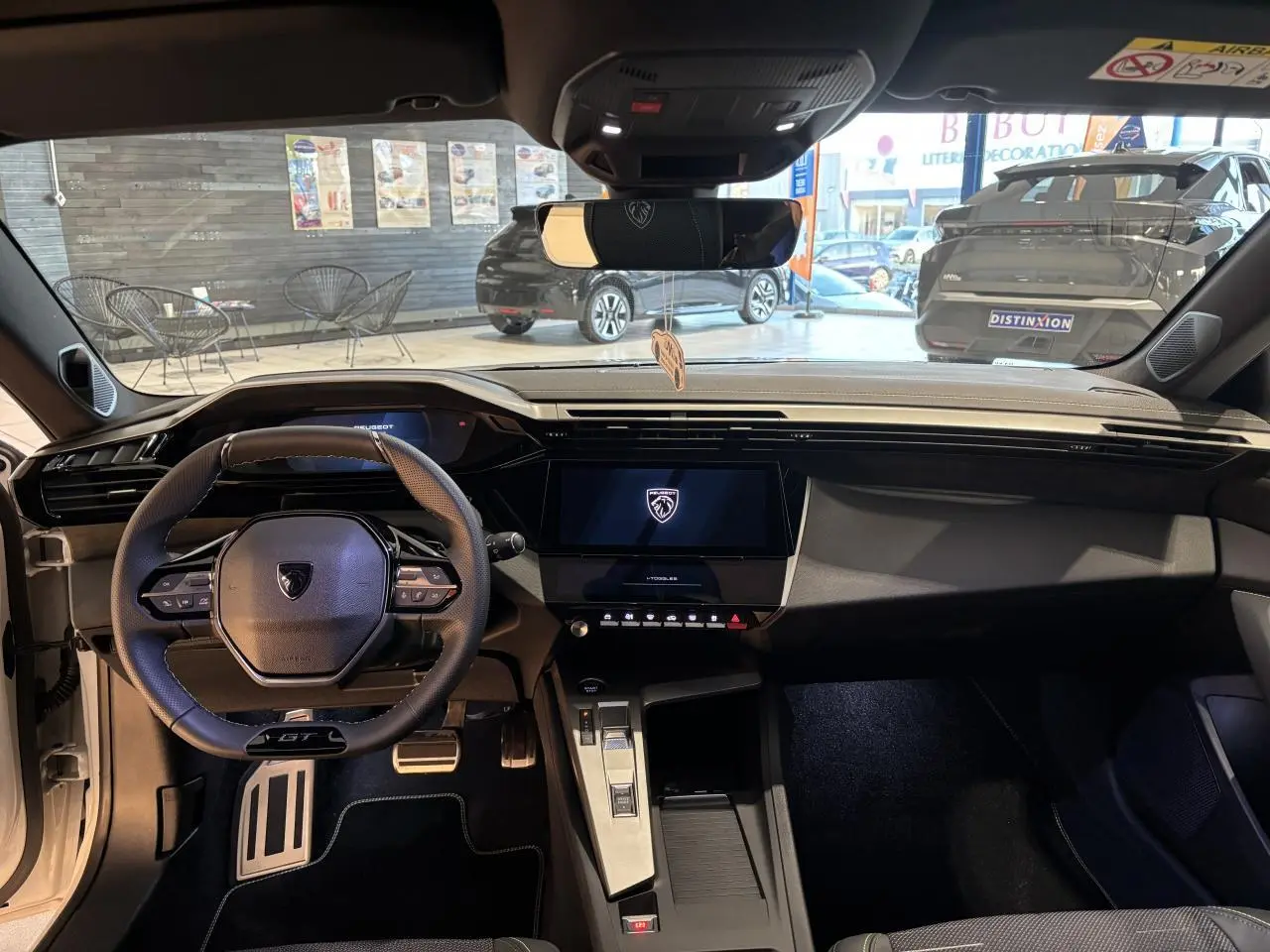 Vue intérieure avant de la Peugeot 308 blanche, volant GT compact, écran tactile central et pédalier aluminium sport.