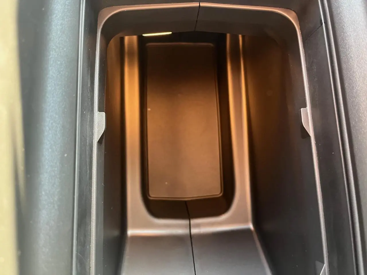 Gros plan sur le rangement central intérieur du Peugeot 3008 gris Artense, éclairé par une lumière ambre douce.