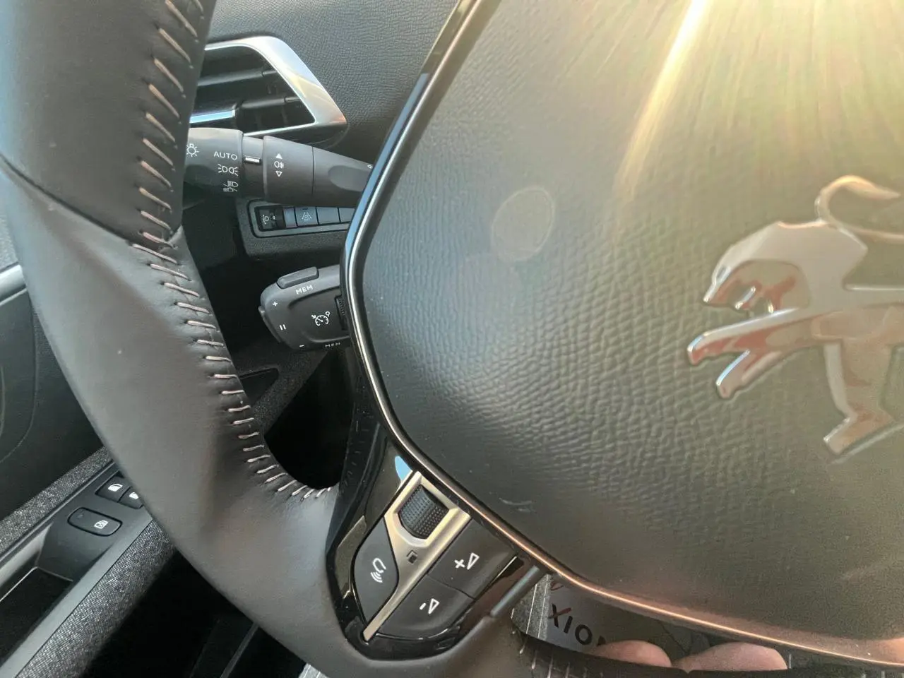 Gros plan sur le volant noir de la Peugeot 3008 2023, avec logo lion et commandes intégrées, lumière naturelle.