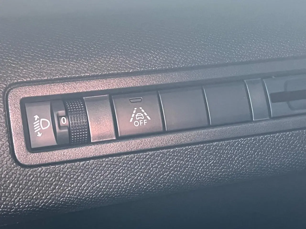 Gros plan sur les commandes de réglage des phares et de l'alerte de franchissement de ligne dans un Peugeot 3008 2023.