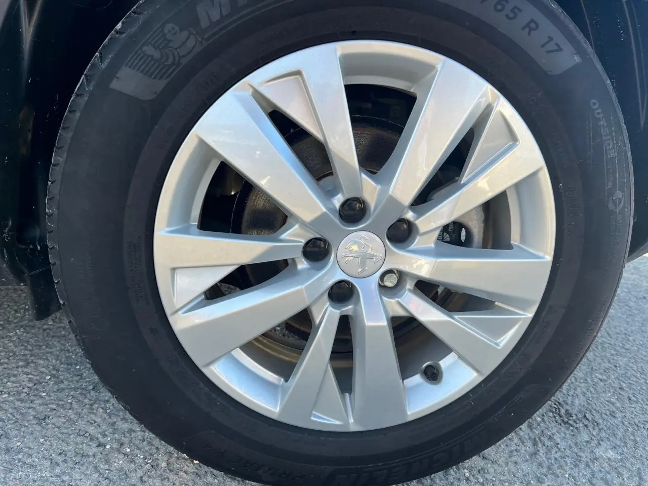 Gros plan sur la jante alliage 17 pouces argentée du Peugeot 3008 gris Artense, avec logo lion au centre.