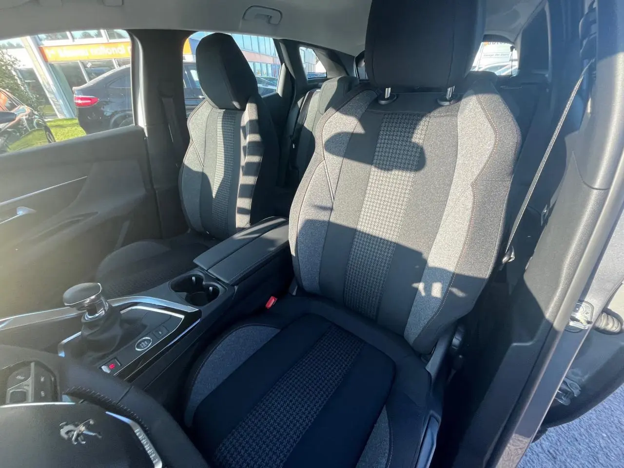 Vue intérieure côté conducteur du Peugeot 3008 2023 avec sièges tissu gris et console centrale avec levier de vitesses.