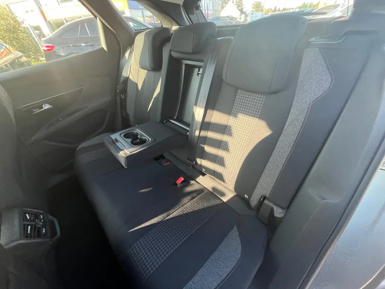 Vue intérieure arrière droite des sièges tissu gris et noir avec accoudoir central déployé du Peugeot 3008 2023 gris Artense.