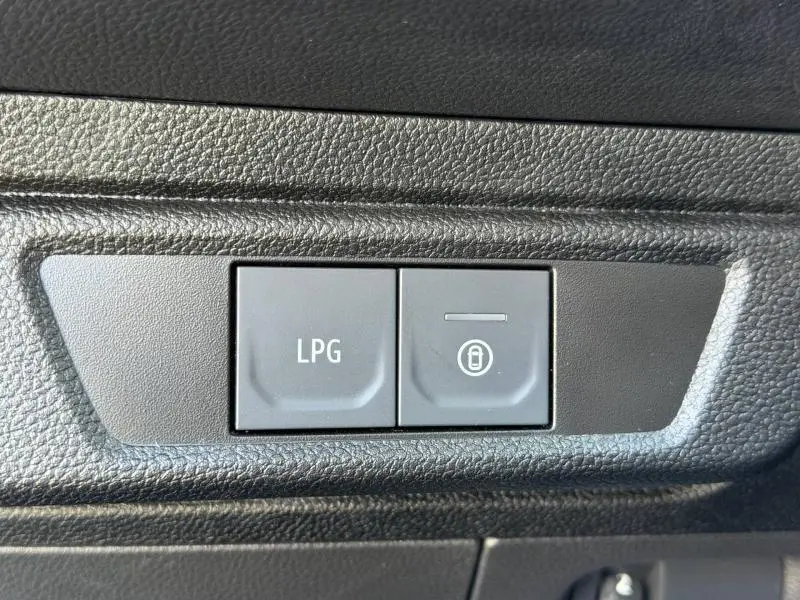 Gros plan sur les boutons de commande LPG et verrouillage intérieur du tableau de bord du Dacia Jogger gris Schiste métallisé.