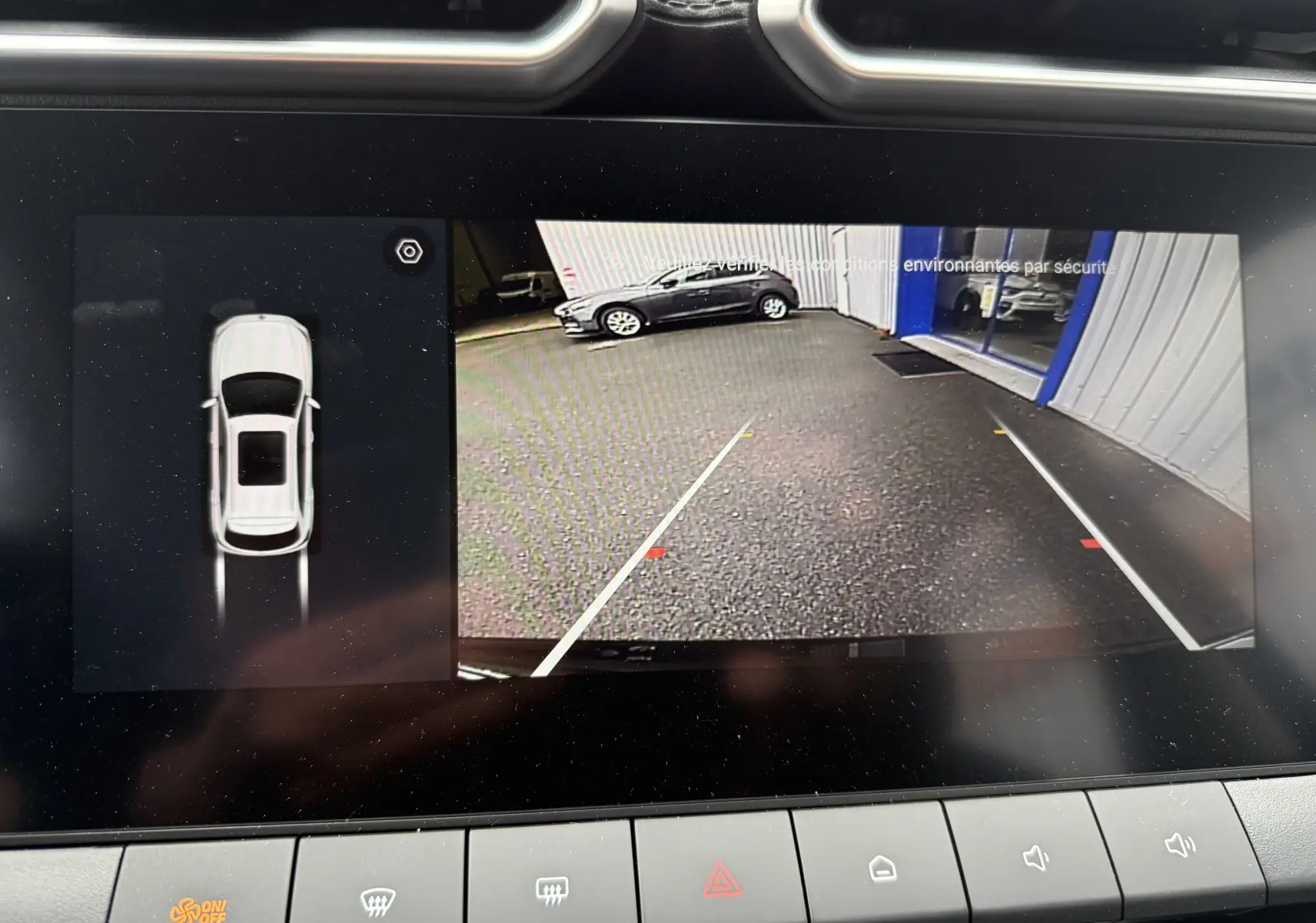 Écran de caméra de recul du MG ZS Pebble Black, montrant l’arrière avec lignes de guidage blanches et vue du parking.