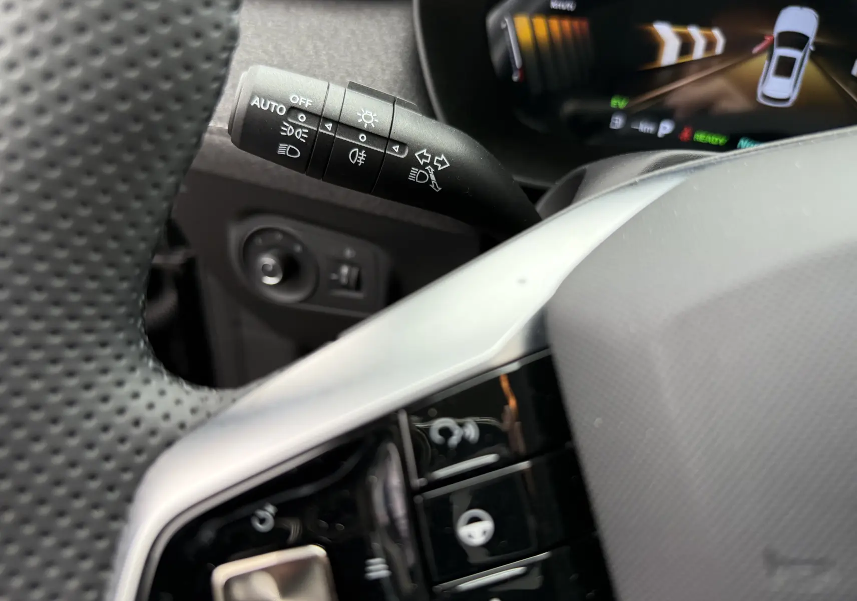 Gros plan sur la manette de commandes d’éclairage et clignotants côté gauche du volant perforé dans l’habitacle noir du MG ZS 2026.