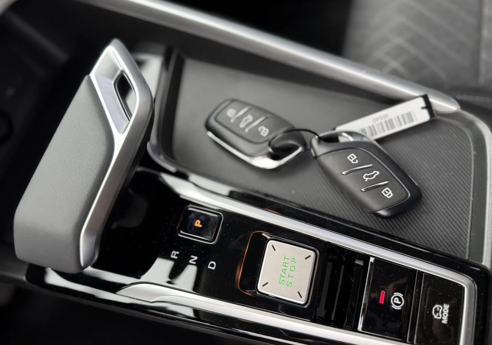 Gros plan sur la console centrale du MG ZS 1.5L Hybrid+ 2026 en Pebble Black, avec levier de vitesses et clés posées.