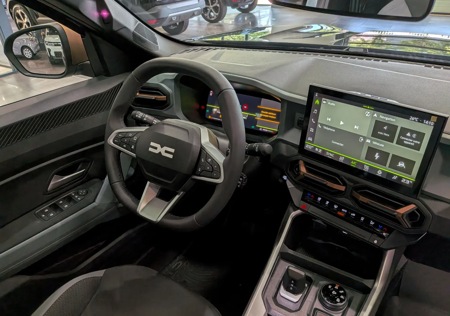 Vue intérieure côté conducteur du Dacia Bigster Hybrid-G 150 4x4 gris, avec tableau de bord numérique et écran tactile central.