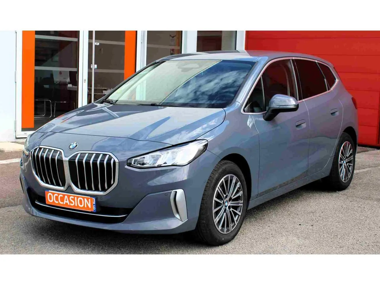 BMW Série 2 Active Tourer gris vue 3/4 avant droit avec calandre chromée et jantes alliage 17 pouces.