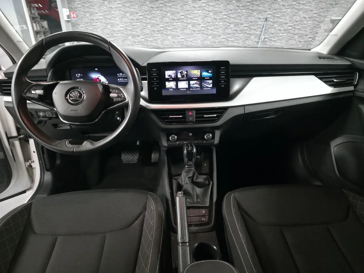 Vue intérieure avant du Skoda Kamiq 2023, tableau de bord noir avec écran tactile central et volant cuir multifonctions.